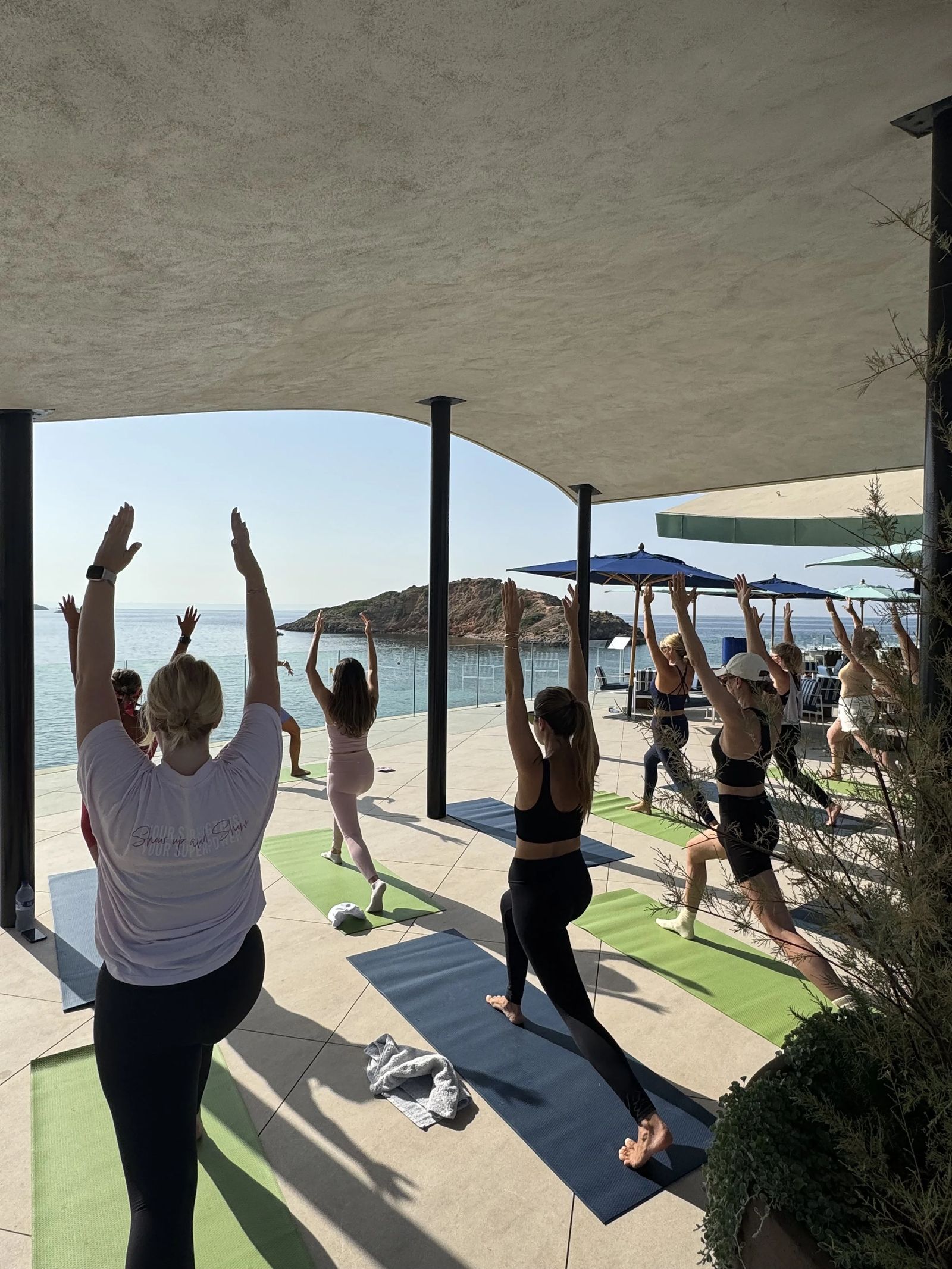 Guests stretching under the pergola at a Mallorca beach club wellness session