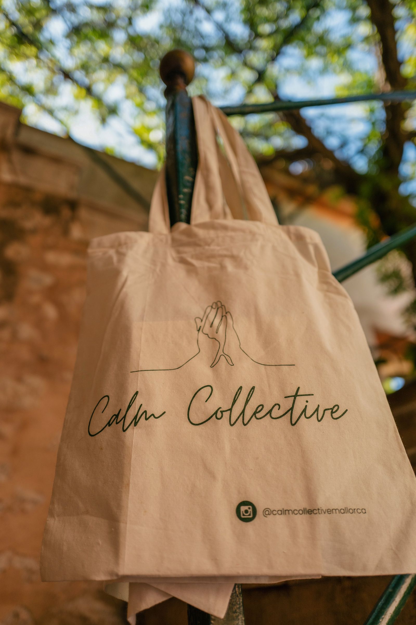 Calm Collective Club natural canvas tote bag hanging at a wellness market in Mallorca